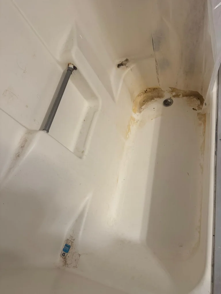 The same tub before cleaning, with built-up grime along the corners and seams