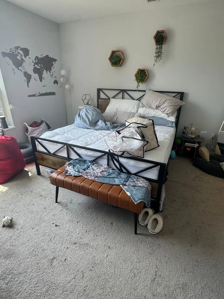 The same bedroom before cleaning, cluttered with belongings and an unmade bed